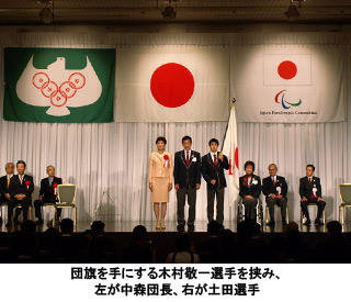 写真：団旗を手にする木村敬一選手を挟み、左が中森団長、右が土田選手