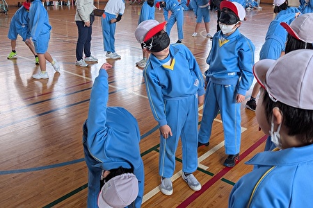 写真:アイマスクをつけて準備体操をする児童