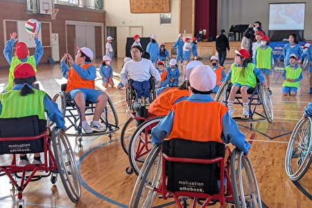 写真:車いすに乗ってバスケットボールをする児童